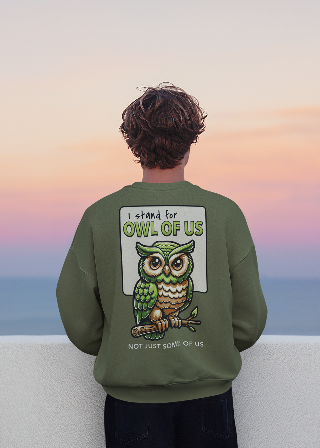 Person wearing a green sweatshirt with an owl graphic and text against a colorful sky.