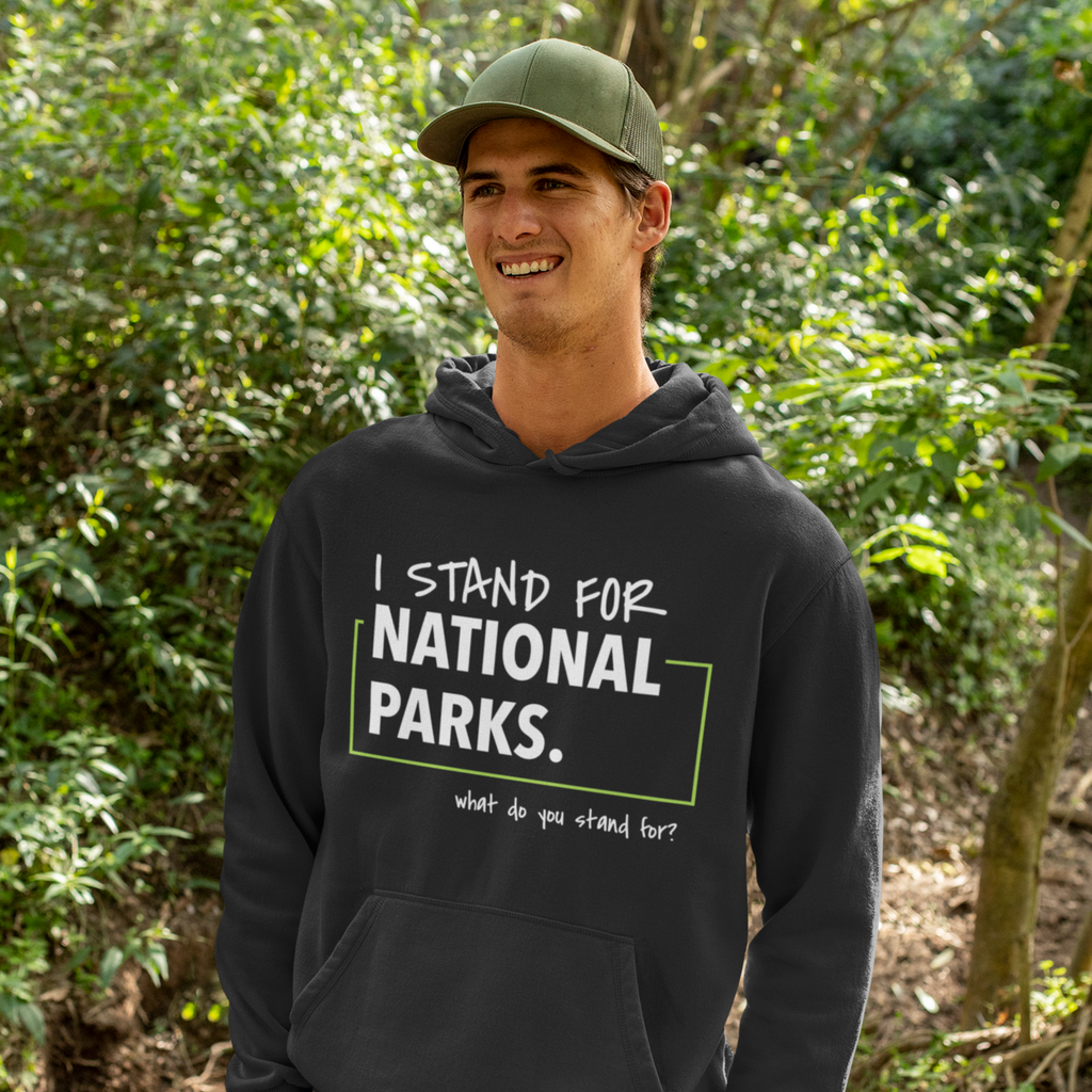 Person wearing a black hoodie with 'I stand for National Parks' text in a forest setting