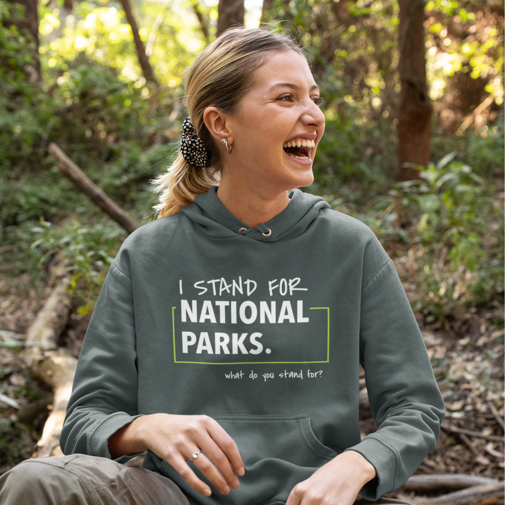Woman wearing a hoodie with 'I stand for National Parks' text in a forest setting