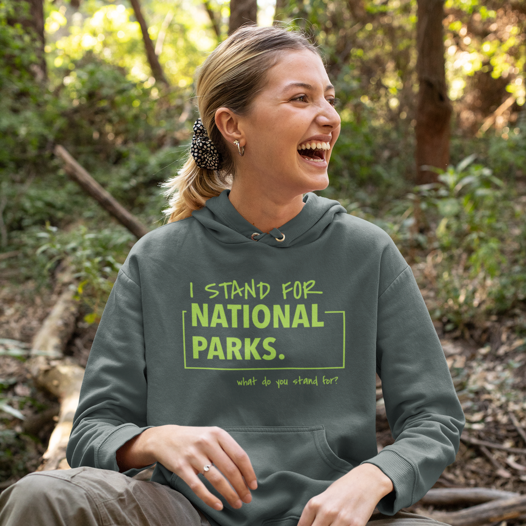 Woman wearing a hoodie with 'I stand for National Parks' text in a forest setting
