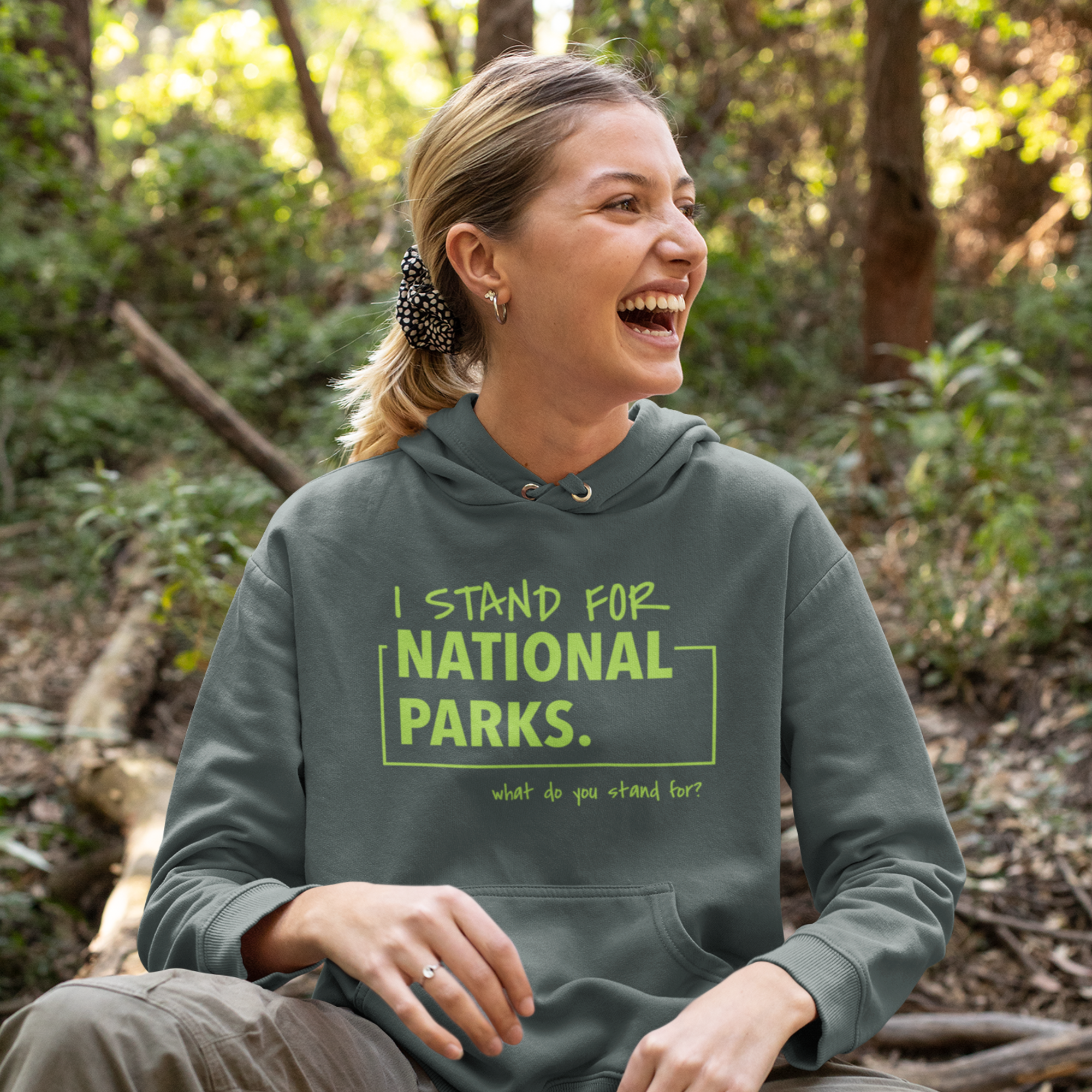 Woman wearing a hoodie with 'I stand for National Parks' text in a forest setting