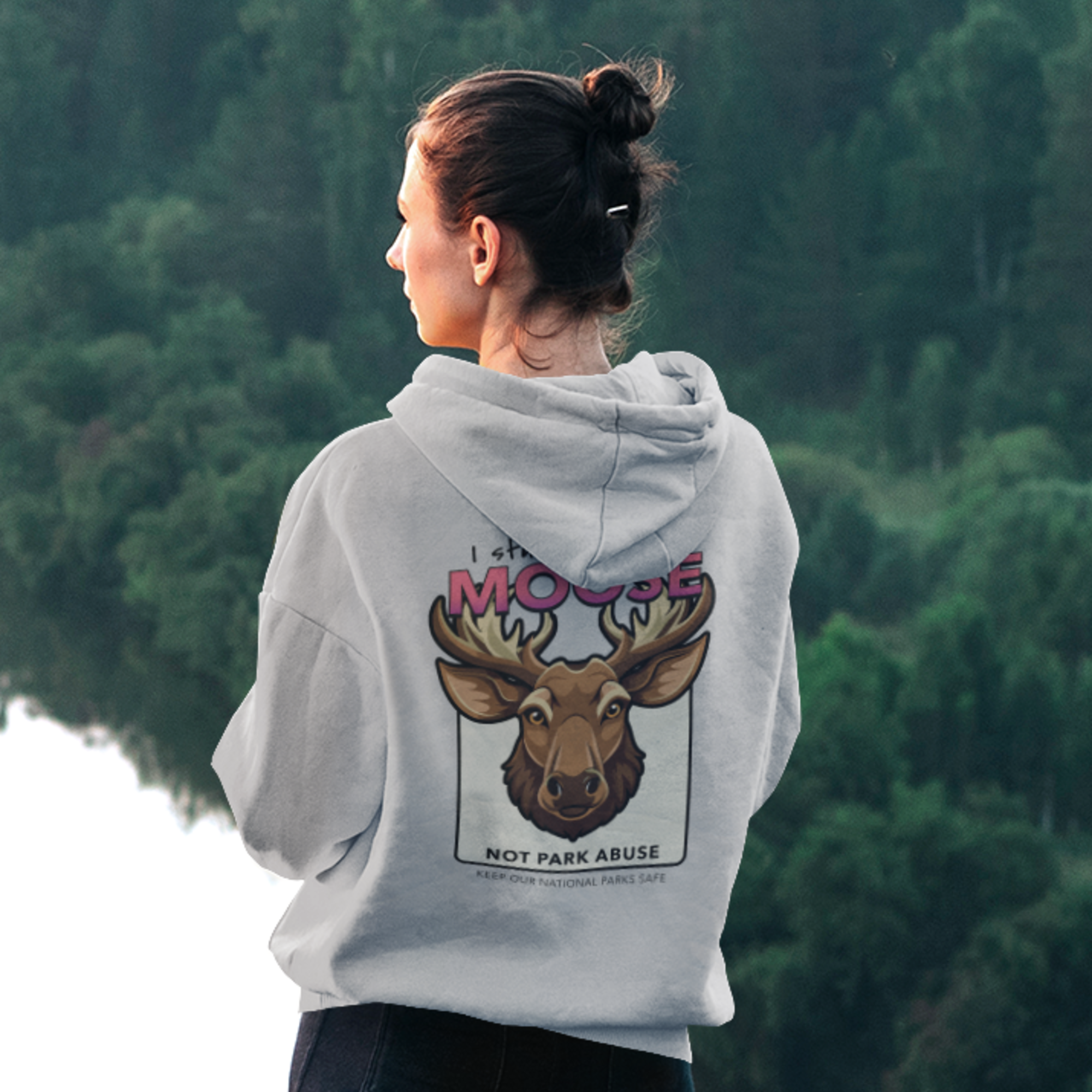 Person wearing a hoodie with a moose design in a forest setting