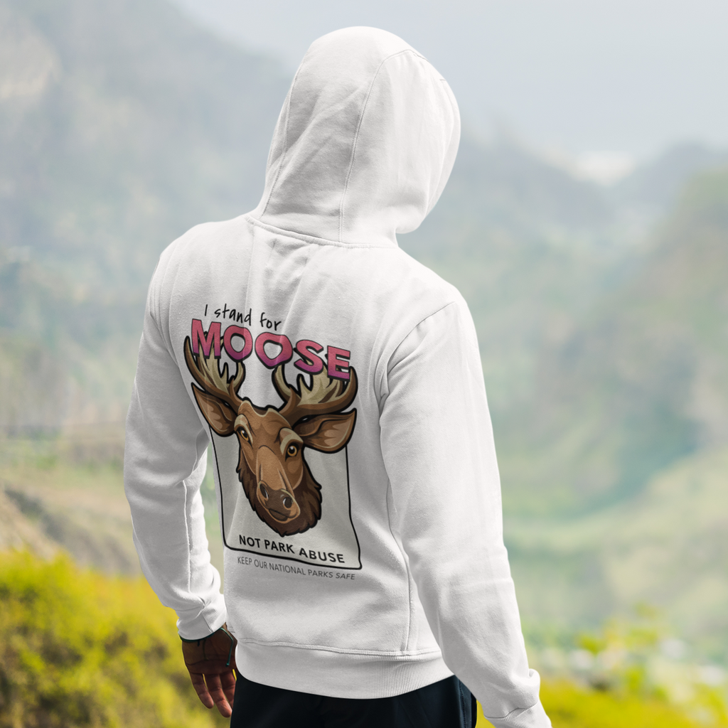 Person wearing a white hoodie with a moose graphic and text in a mountainous landscape
