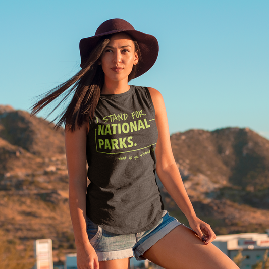 Woman wearing a tank top with 'Stand for National Parks' text, standing against a mountainous landscape.