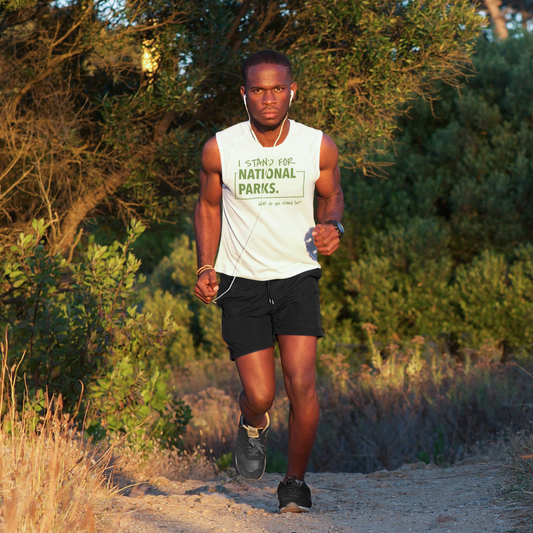 Man running on a trail with trees with a I stand for national parks tank top. 