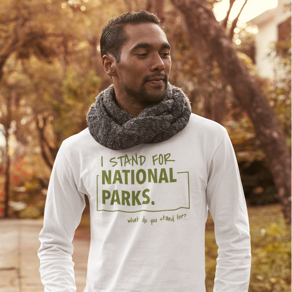 Man wearing a white shirt with 'I stand for National Parks' text in a park setting