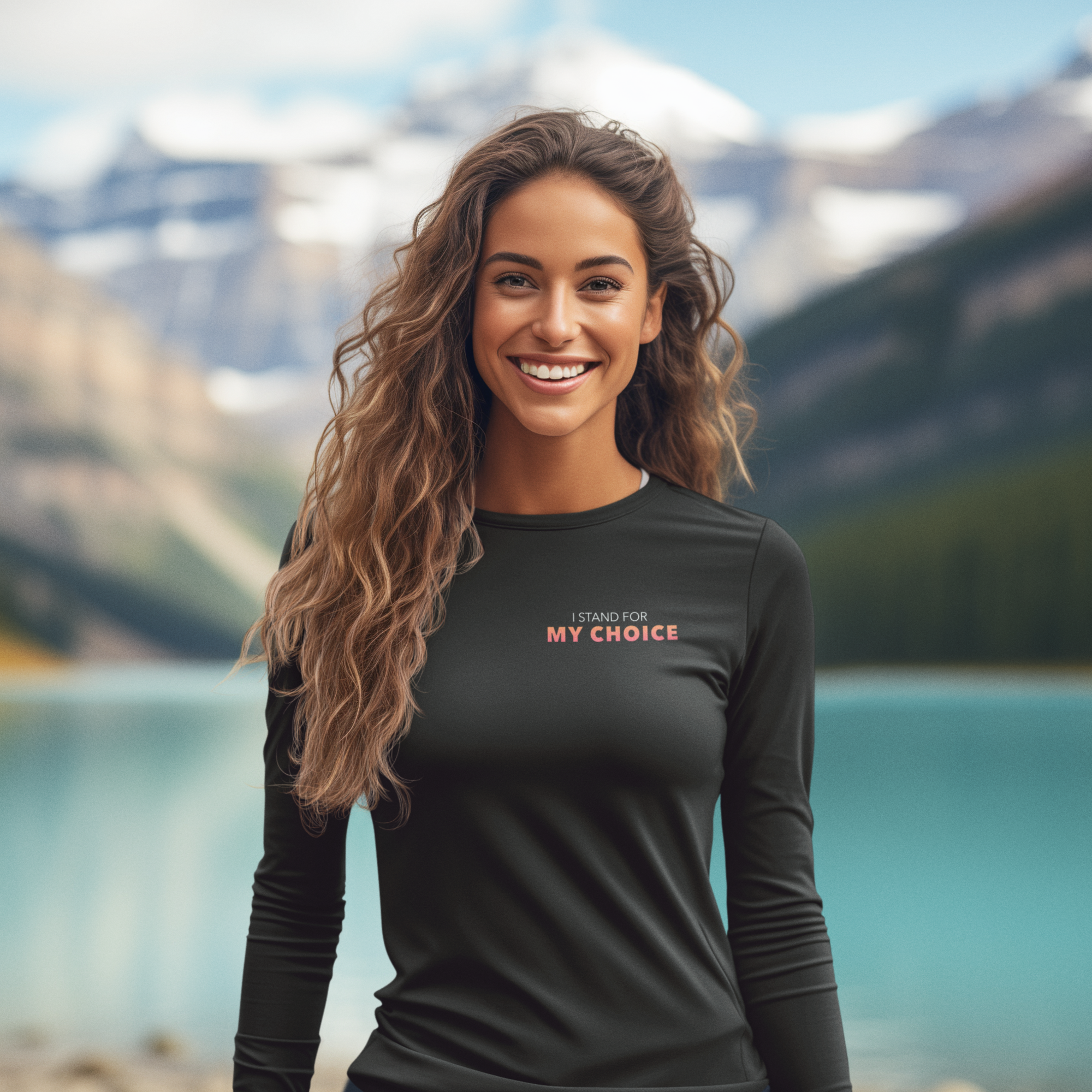 Woman wearing a black shirt with text standing in front of a mountain lake